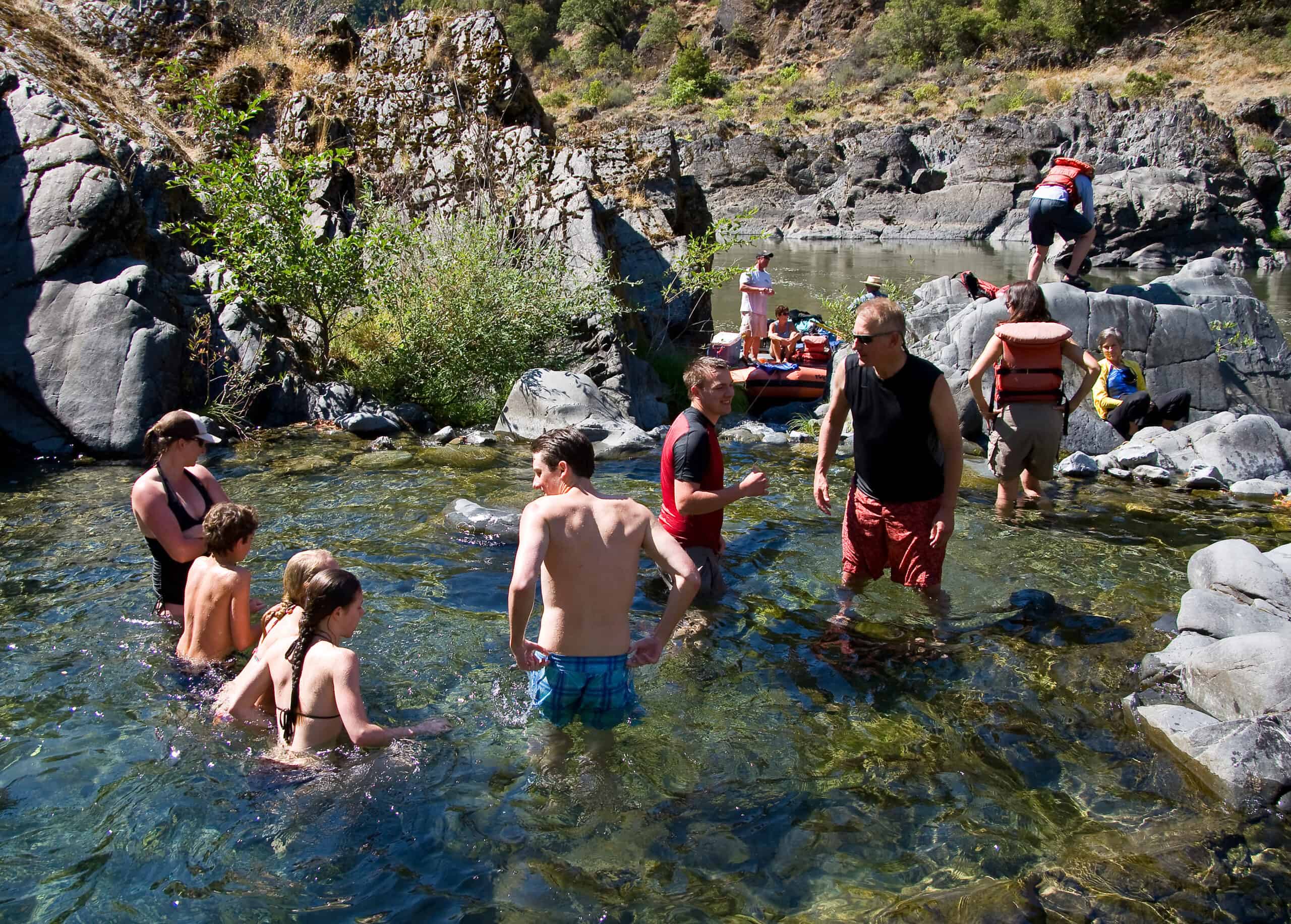 Guests exploring a clear Rogue River swimming hole