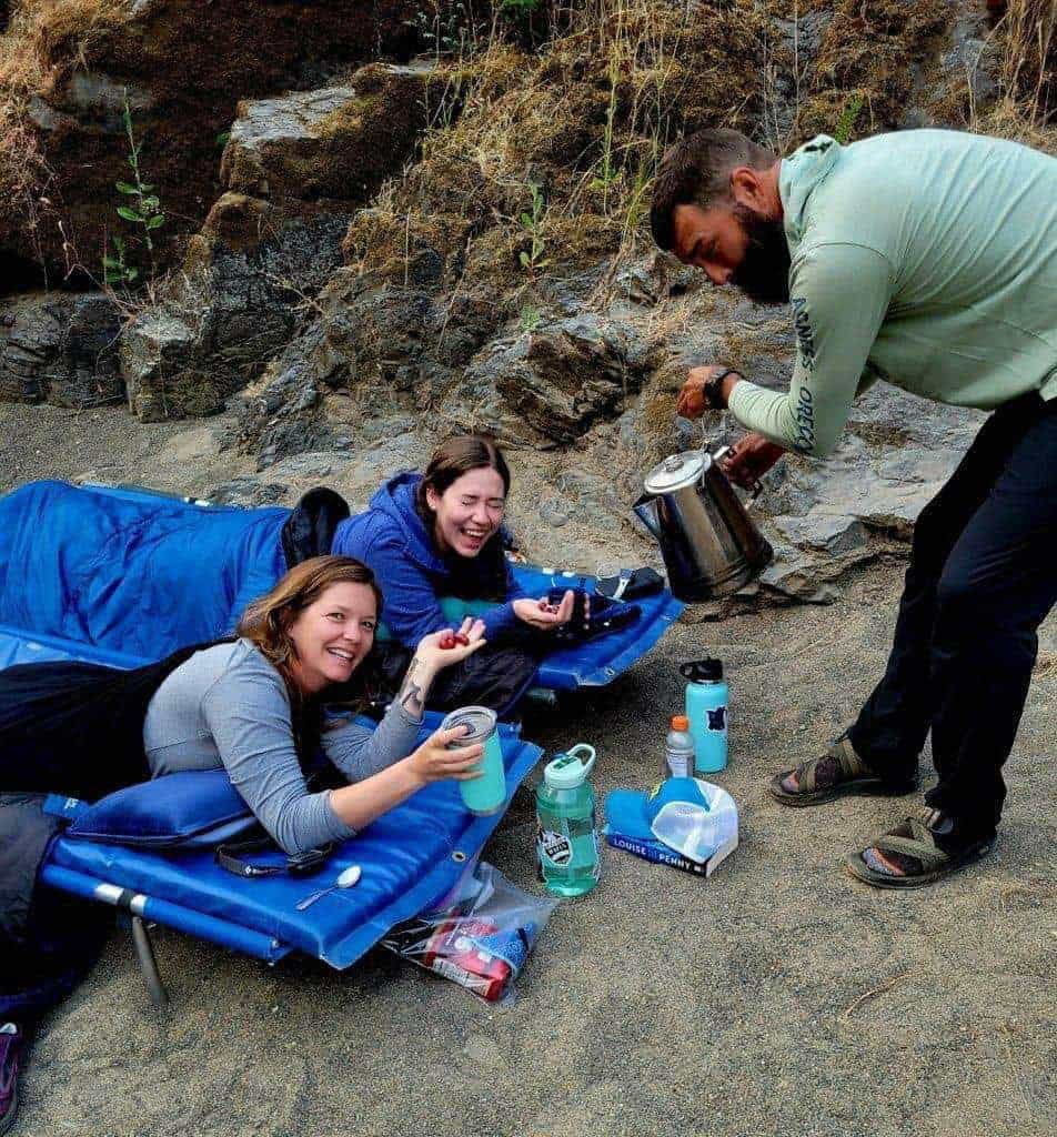 Guests relaxing on comfortable riverside camp cots